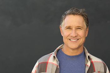 Smiling man in front of gray background