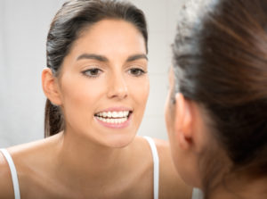 Woman examining healthy teeth in mirror